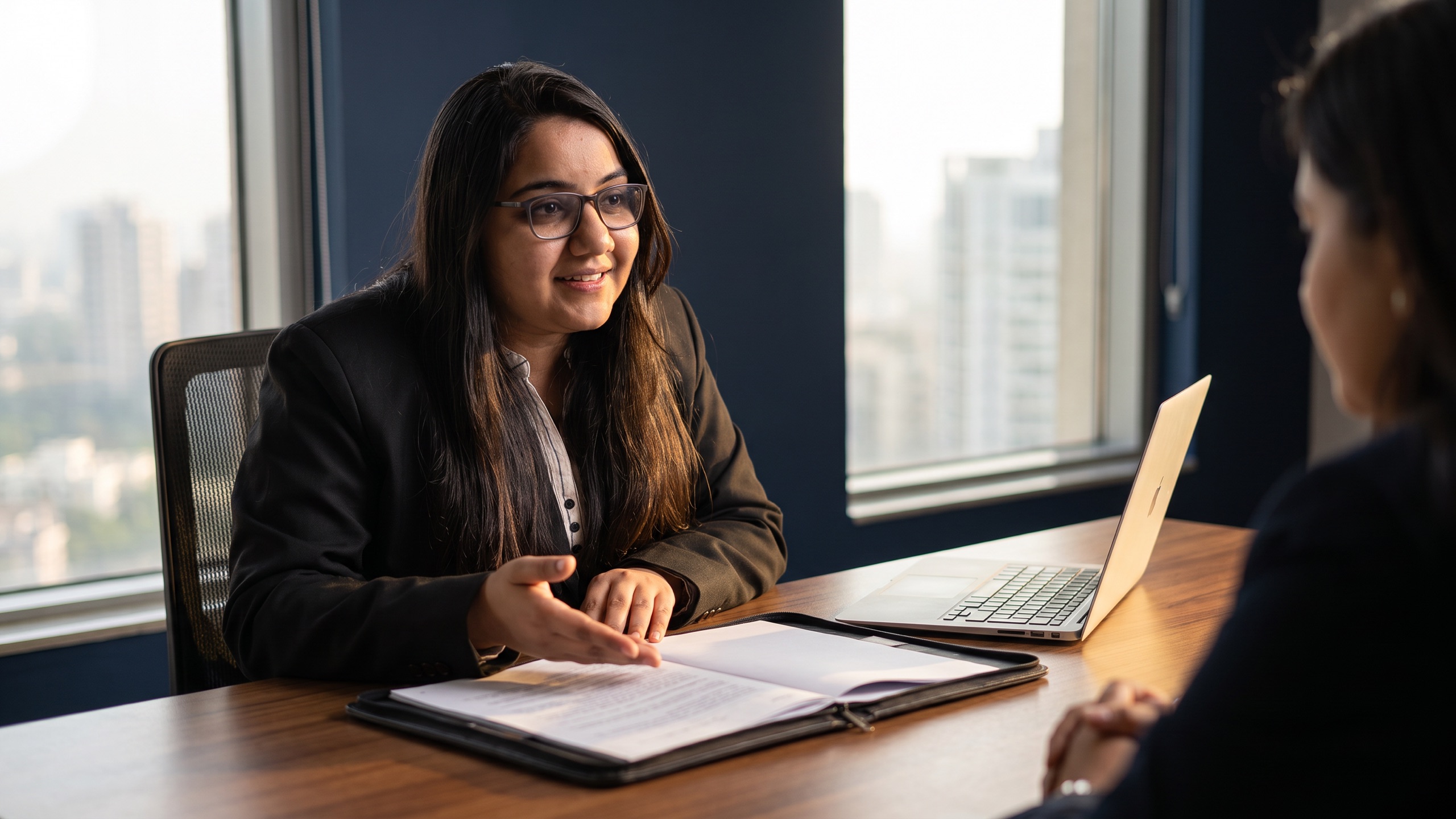A chartered accountant seated across a desk from a client, talking through tax planning options with working papers open between them.